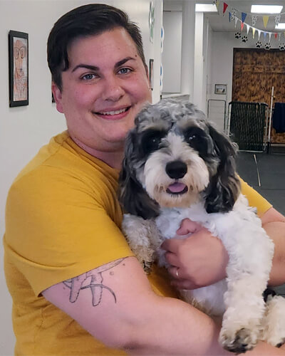 AP, dog walker and pet caregiver at Four-Legged Fun Zone in Everett, WA, smiling while holding a small companion dog. AP is part of the team providing dog walking and pet care services for local pet owners.